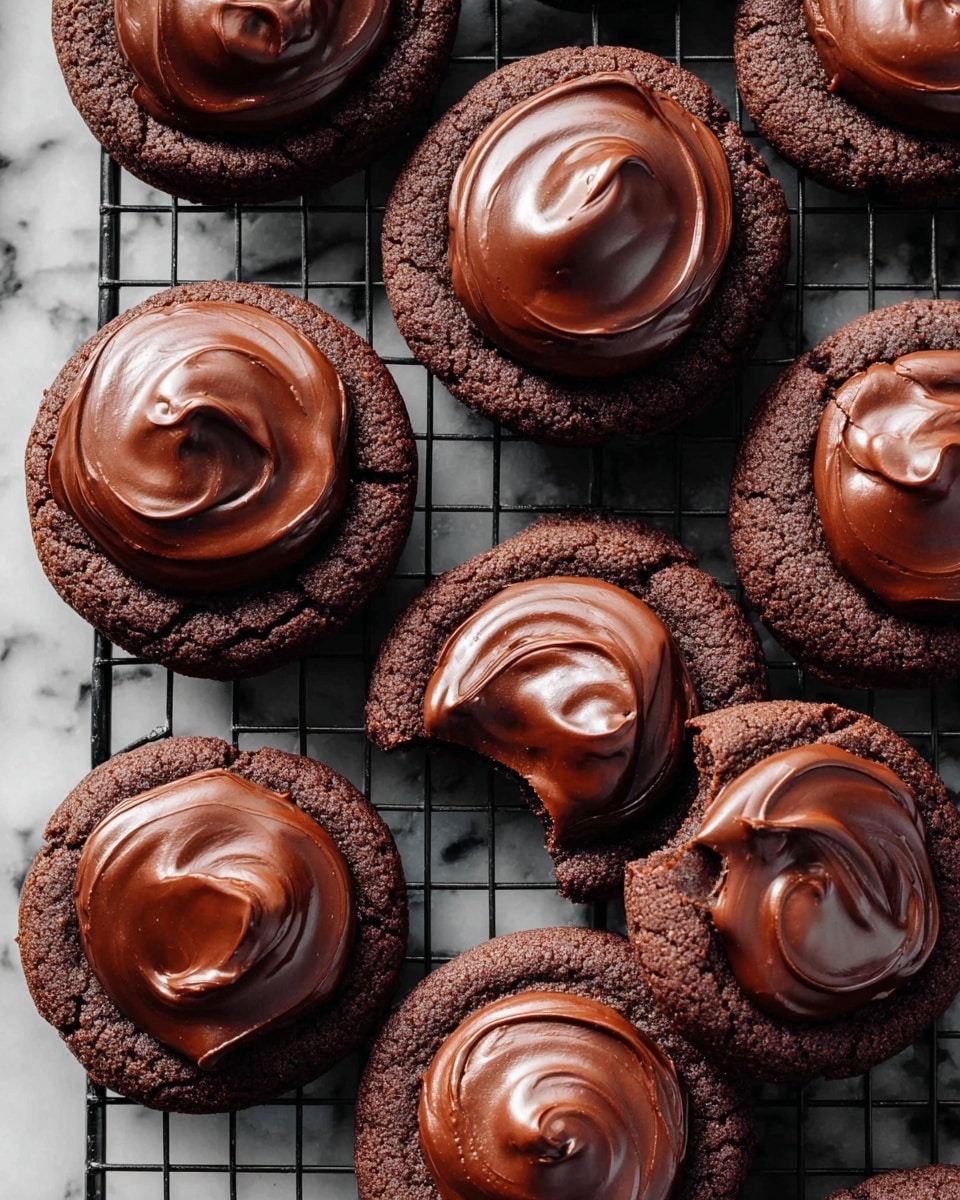 The image shows a close-up of ten round chocolate cookies with a thick, smooth layer of glossy dark chocolate spread on top of each cookie. One cookie has a bite taken out, revealing a soft, chewy interior beneath the shiny chocolate layer. The cookies are placed on a black metal cooling rack over a white marbled surface. The chocolate topping is swirled gently, creating a textured, creamy look with slight peaks and curves. The cookies are evenly spaced with some edges slightly overlapping. photo taken with an iphone --ar 4:5 --v 7
