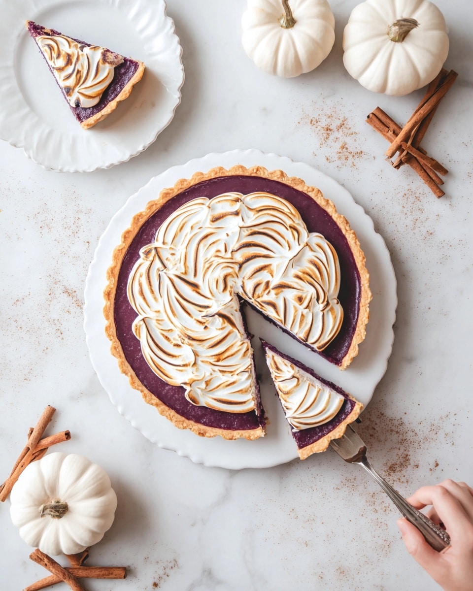 A round tart with a golden brown crust and a deep purple filling fills most of a white plate on a white marbled surface. The tart is topped with a thick layer of lightly toasted meringue, swirled in soft, curved peaks with golden brown edges, placed in the center covering part of the filling. One slice is slightly separated, and another slice with the same layers lies on a white scalloped plate nearby. Around the setting, there are small white pumpkins, cinnamon sticks, and scattered cinnamon powder adding a warm touch. Woman’s hand holding a silver utensil is pulling a slice from the tart. Photo taken with an iphone --ar 4:5 --v 7