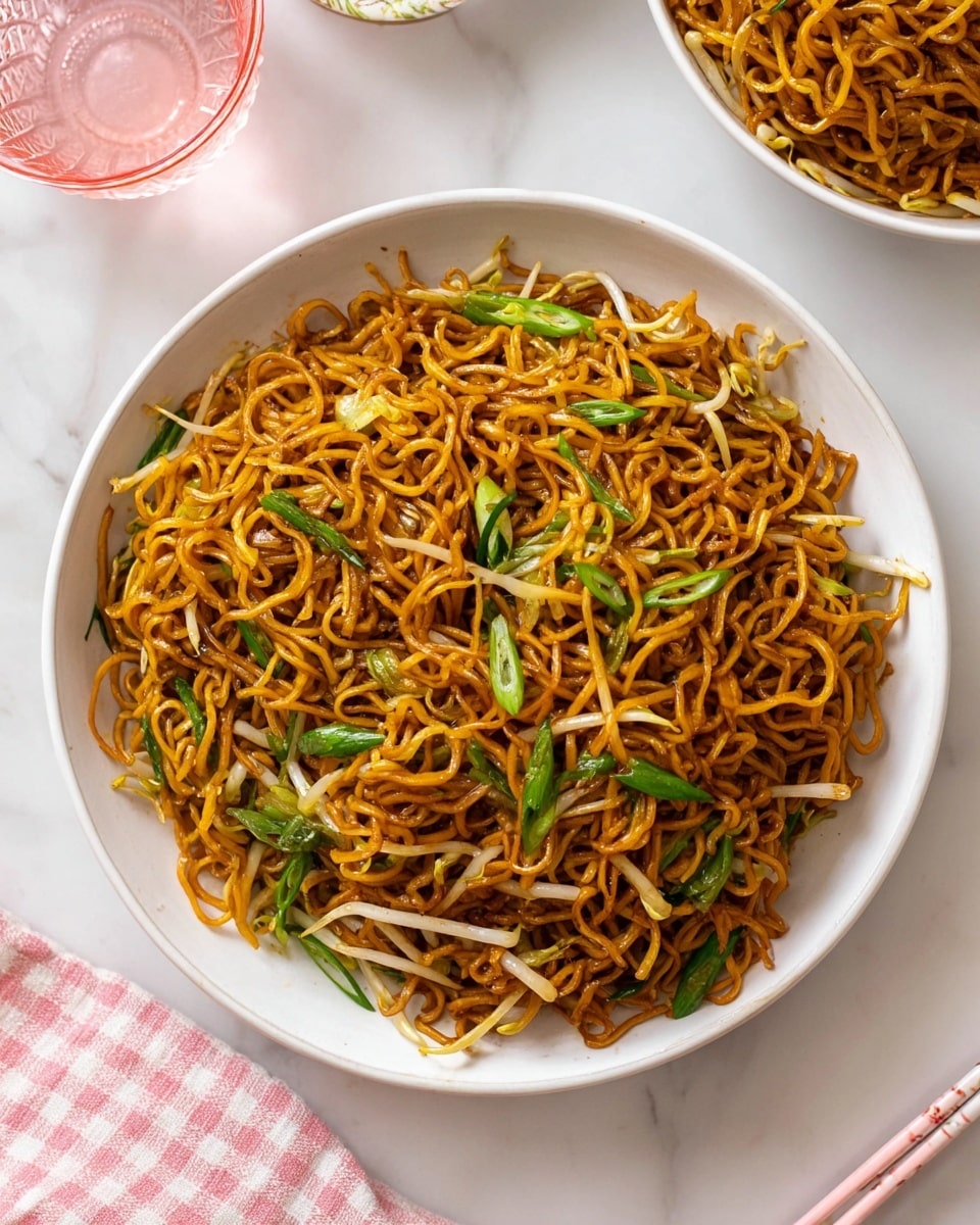 A large white bowl filled with a generous serving of stir-fried noodles forms the central focus. The noodles have a rich golden-brown color and a slightly shiny texture, tangled together with light beige bean sprouts and green scallion pieces scattered throughout. The bowl sits on a white marbled surface. Nearby, a pink and white checkered cloth and a glimpse of a pink glass with water add soft color accents, along with a pair of pale pink chopsticks resting next to the bowl. Part of another white bowl with more noodles is visible at the top edge of the image. Photo taken with an iphone --ar 4:5 --v 7