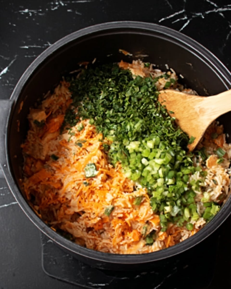 A black pot filled with a mixed dish that has three visible layers: the bottom layer is light brown rice with orange cheese mixed in, the middle layer has small pieces of orange food mixed with the rice, and the top layer consists of green chopped scallions and parsley covering half of the pot. A wooden spoon is stirring the mixture from the right side with some of the orange and rice ingredients on it. The pot sits on a black surface with a white marbled texture. photo taken with an iphone --ar 4:5 --v 7