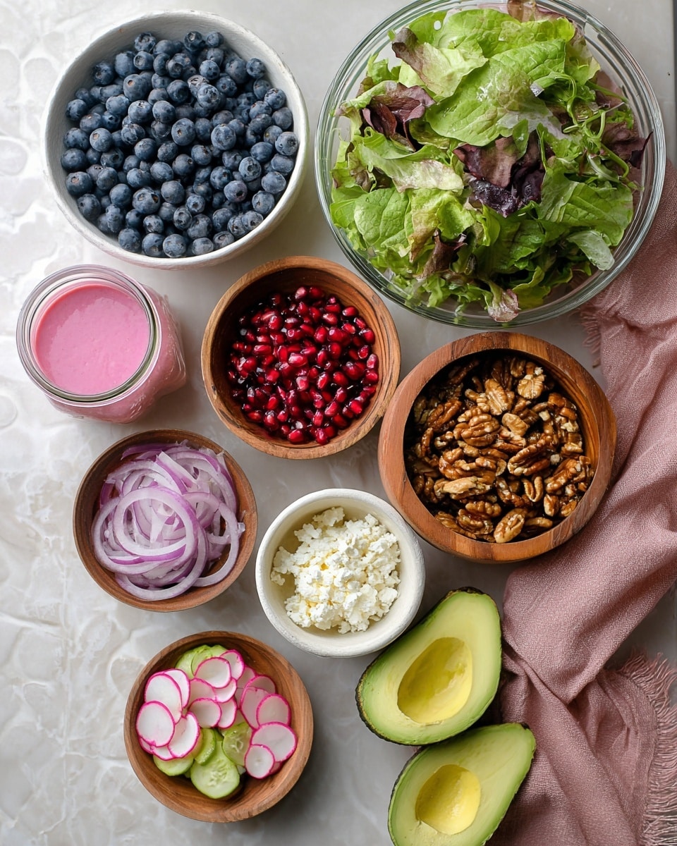 The image shows several white bowls and a wooden bowl arranged on a white marbled surface. A large glass bowl filled with mixed green salad leaves sits at the top right. Below it, a large white bowl holds fresh blueberries, next to a small white bowl filled with bright red pomegranate seeds. To the right of the pomegranate is a wooden bowl full of roasted nuts. Near the bottom, there is a small white bowl with thin slices of red onion, a smaller white bowl with crumbled white cheese, and a bowl of thinly sliced pink and green radishes. To the right, two halves of an avocado with smooth green flesh and a dark pit sit on a folded pink cloth. A small glass jar with pink dressing is placed to the left of the blueberries. The overall arrangement is colorful and fresh. photo taken with an iphone --ar 4:5 --v 7