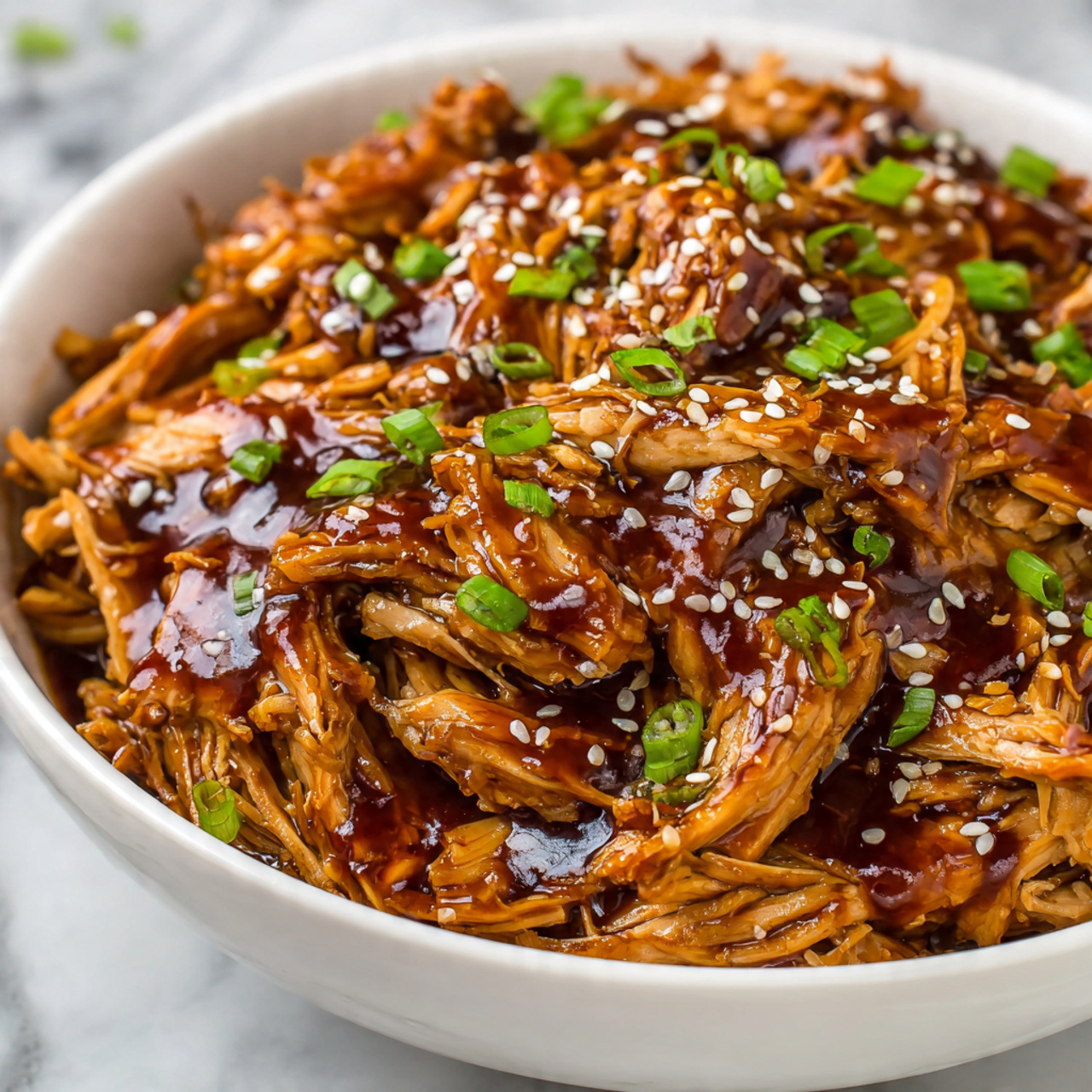 The image shows a white bowl filled with shredded chicken coated in a shiny, dark brown sauce. The chicken pieces are layered to show their tender, moist texture, with the sauce adding a glossy finish. On top, there are small white sesame seeds sprinkled evenly and chopped bright green spring onions scattered around, adding color contrast and freshness. The bowl sits on a white marbled surface. photo taken with an iphone --ar 4:5 --v 7